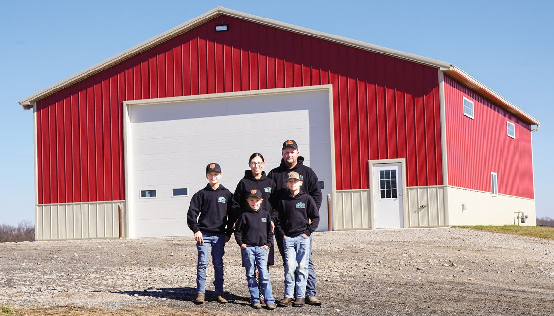 Co-op members posing in front of a pole barn built by the company their family owns and operates.