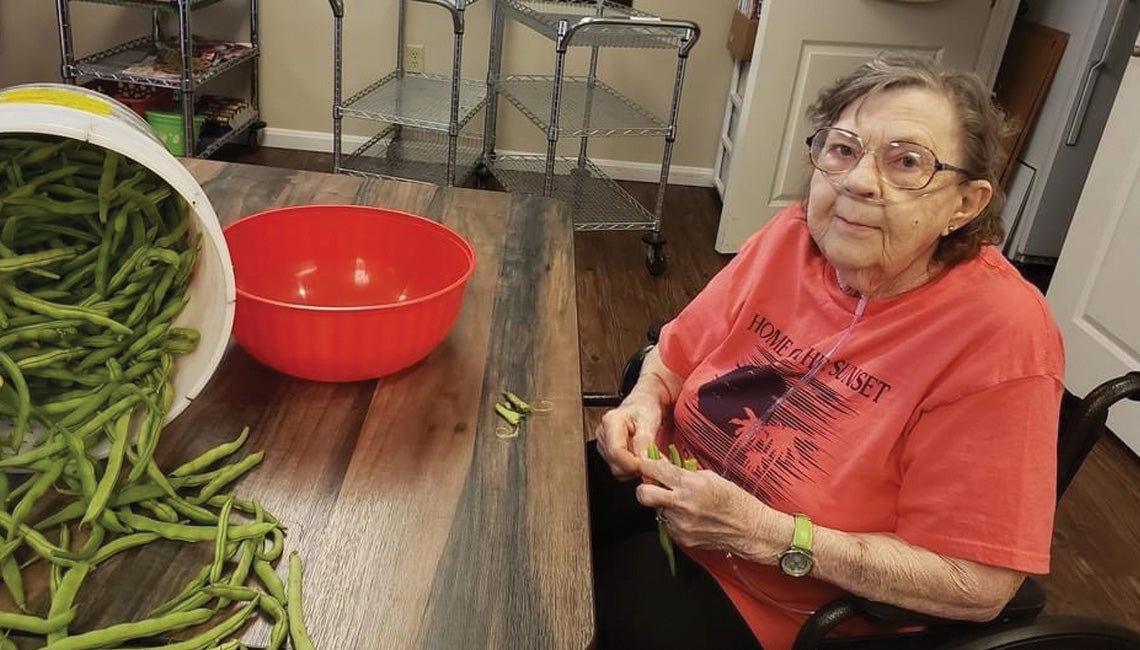 Resident at Woodland Country Manor helps with prepping green beans.