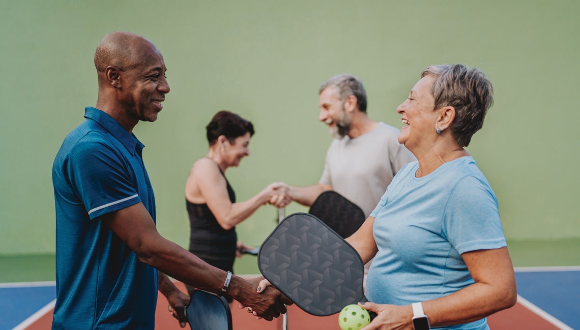 Athletes shaking hands after a pickleball match.