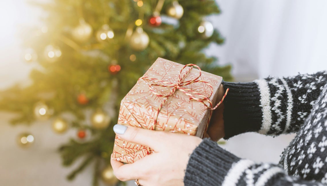 A Christmas present beside a Christmas tree