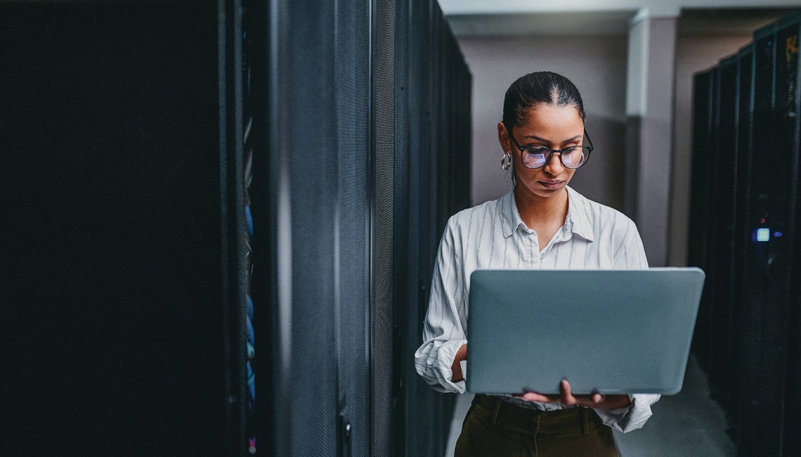 A woman standing and holding a laptop