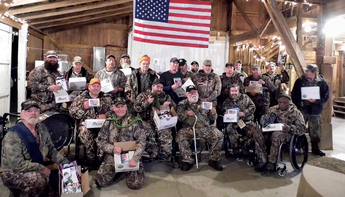 A group of veterans standing indoors under an American flag