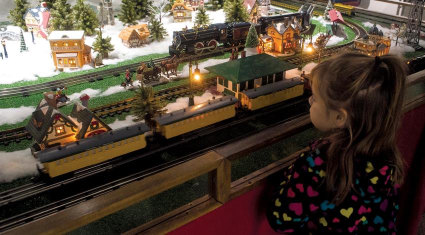 A young girl admires a toy train set