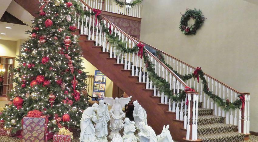 A staircase decorated for Christmas as well as a giant Christmas tree and manger.