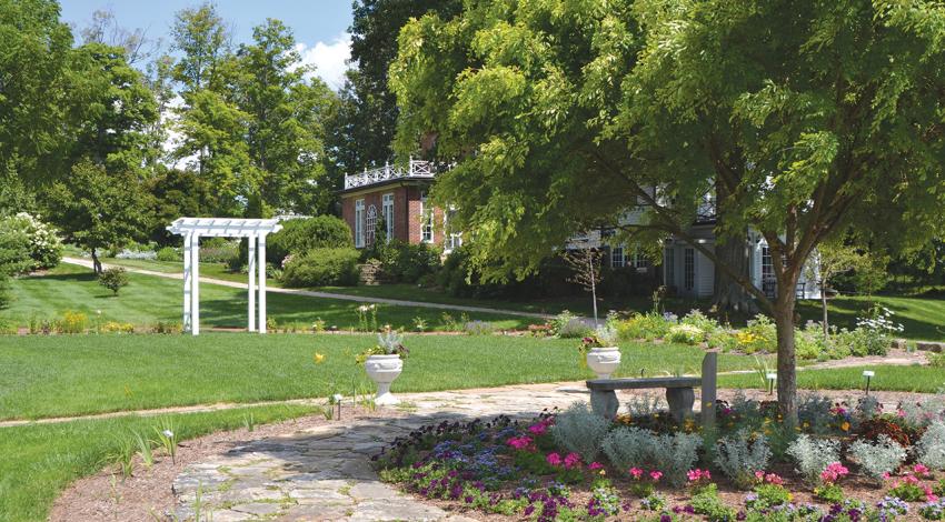 A picture of the arboretum including trees, an archway, and flowers.