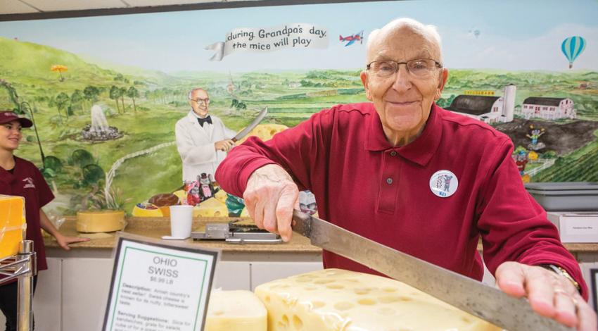 A man smiles with a giant block of cheese.