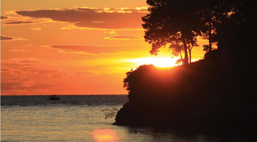 The sun sets behind an island on Lake Erie