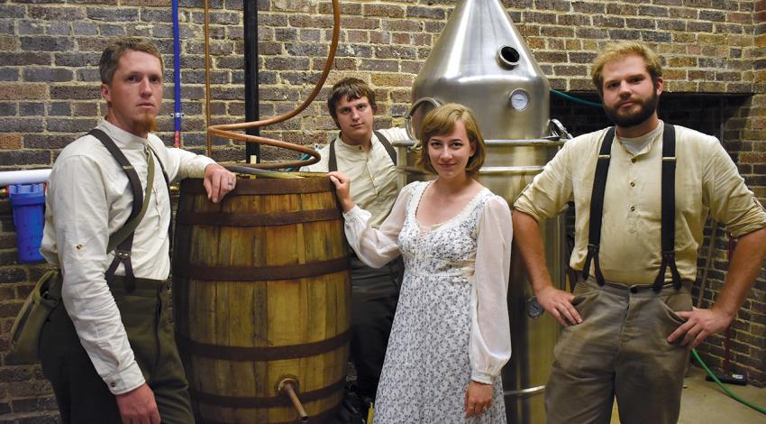 Hocking College students in period clothing pose with the distilling equipment in New Straitsville.