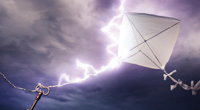 Kite with key on string in front of stormy sky