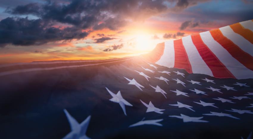 An American flag flying over a sunset