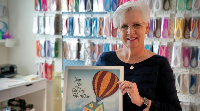 A woman standing with a piece of her artwork