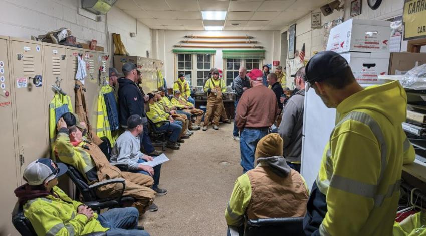 A group of lineworkers having a team meeting