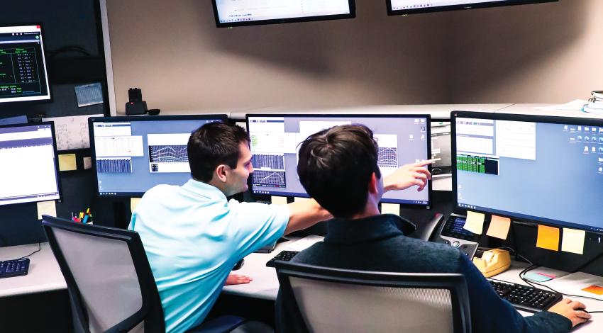 Two men sitting in front of computer monitors