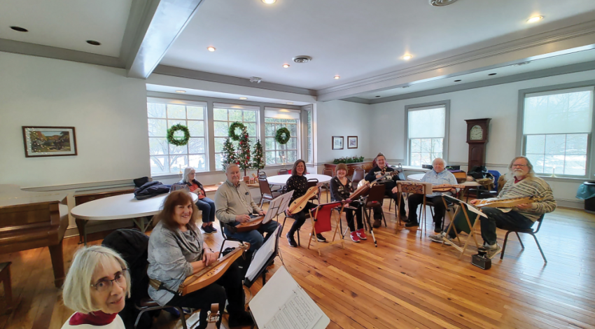 A group of people sitting with instruments, playing music 