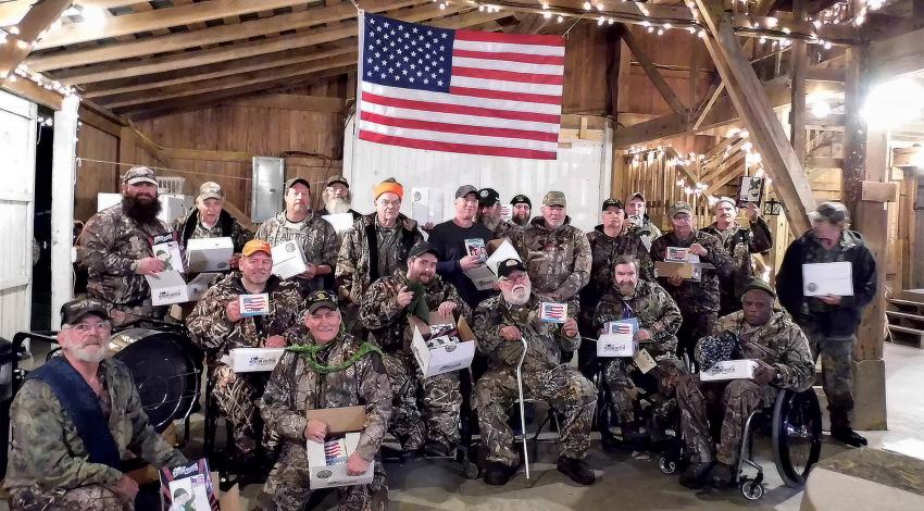 A group of veterans standing indoors under an American flag