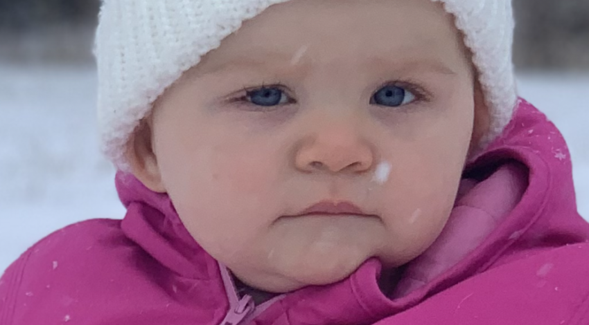 baby in pink snowsuit and white hat