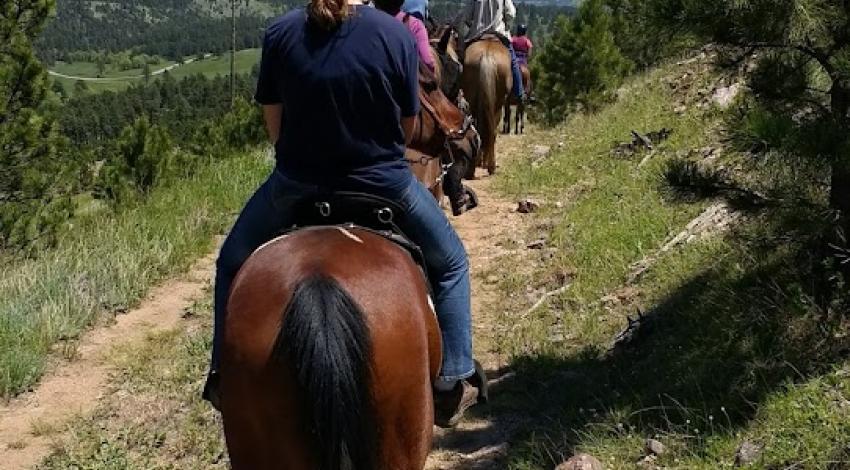 people on horseback on trail overlooking vista