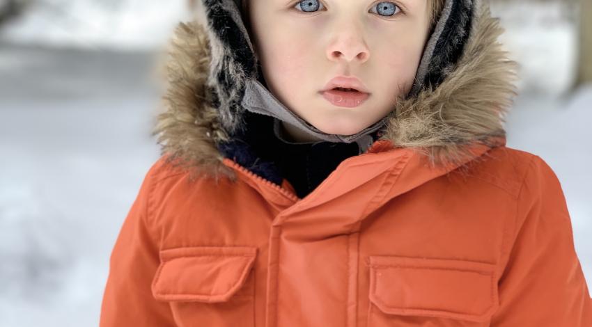boy in winter coat and fuzzy hat in the snow