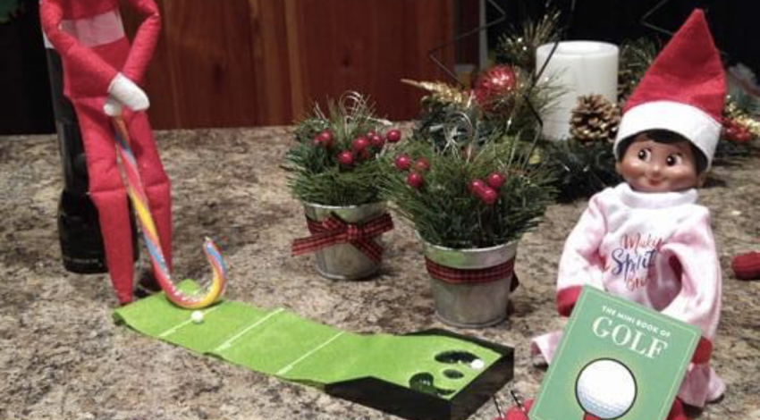 Elf on the Shelf holds upside-down candy cane by tiny putting mat