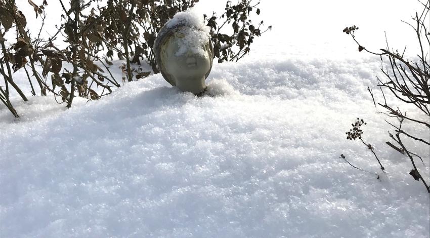 statue head sticks up from snow pile