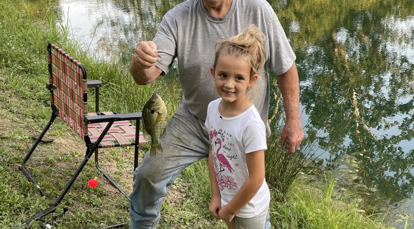 man holding a fish for a little girl
