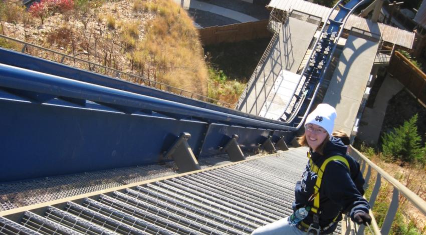 young woman climbing stairs along roller coaster track