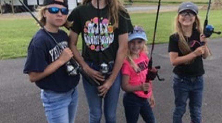 four kids holding fishing poles