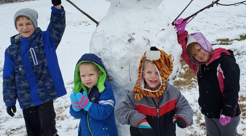 four children posing with giant snowman
