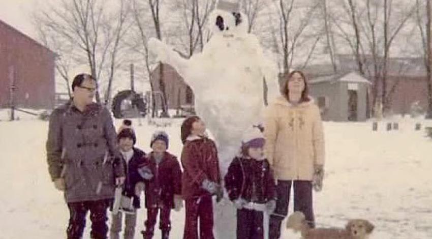 Family and dog around a giant snowman