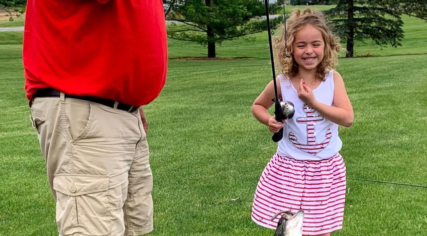 Little girl smiling at a fish