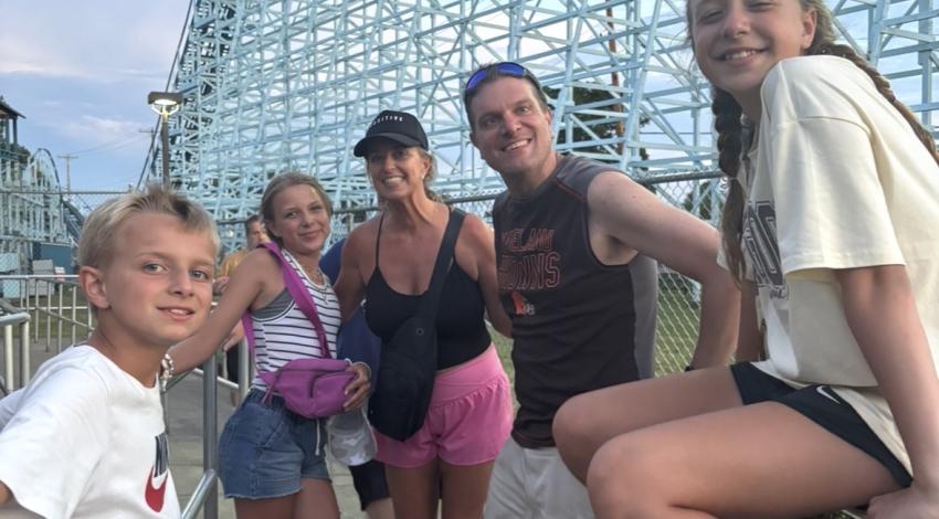 family in front of roller coaster