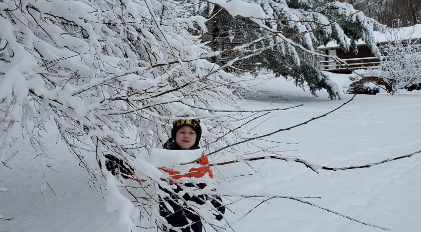 Boy next to snow-covered tree