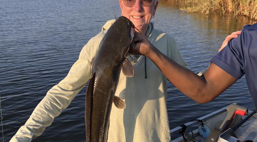 Woman smiling while a guide holds her fish
