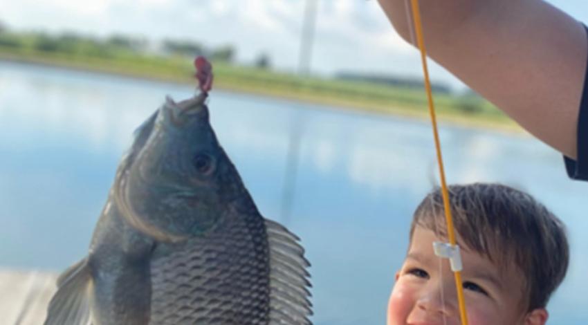 boy smiling while holding a fish