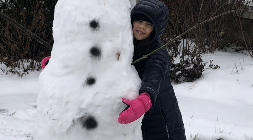 little girl hugging tall snowman