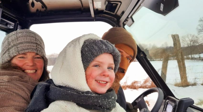 Man, woman, and girl in vehicle in snow