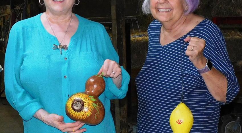 two women holding painted gourds