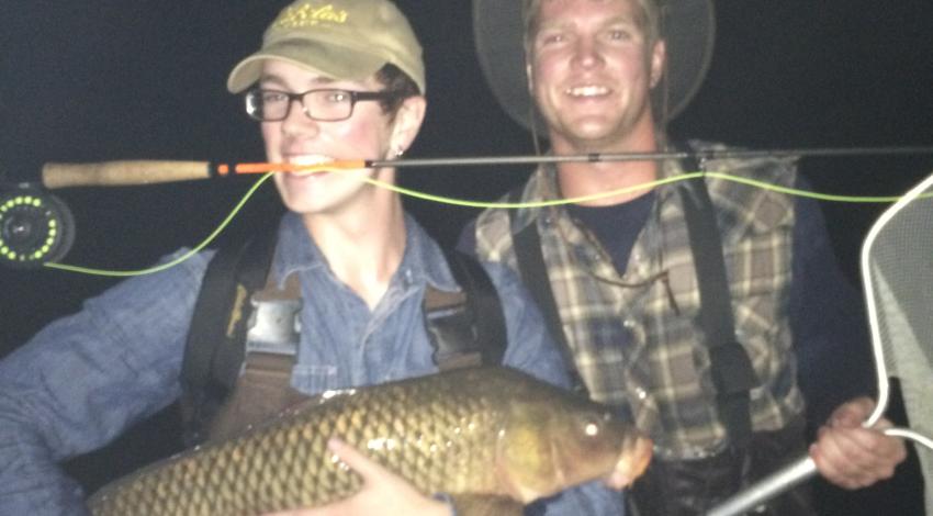 two boys smiling holding a large fish