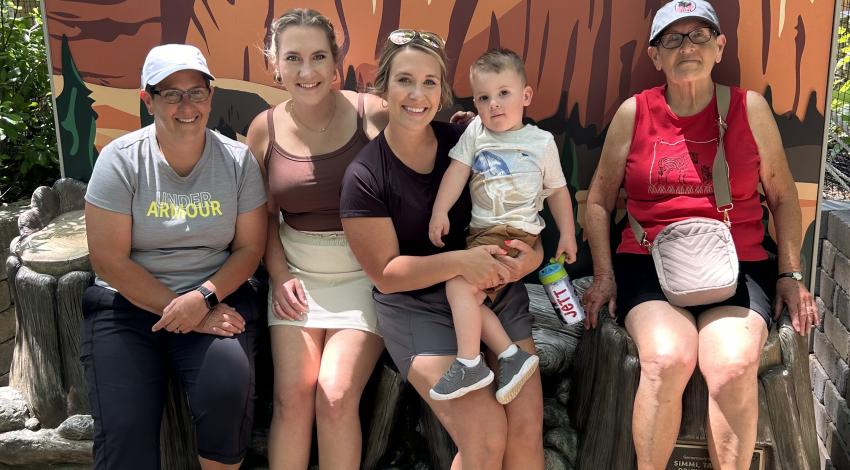 family sitting in front of Toledo Zoo sign