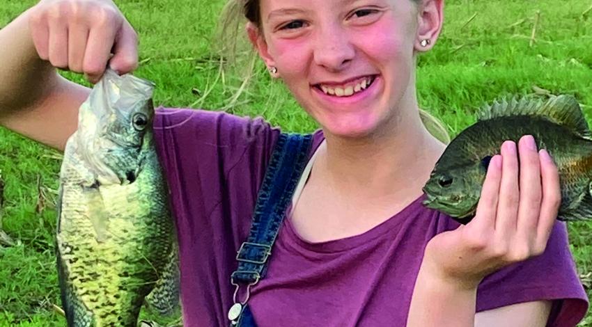 girl smiling holding two fish