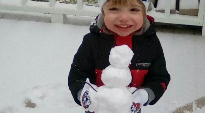 small child on snowy deck holding tiny snowman
