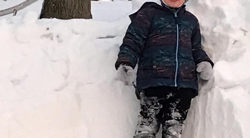 boy standing in front of snow fort