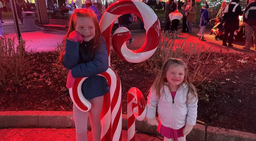 Two girls next to large plastic candy canes outdoors