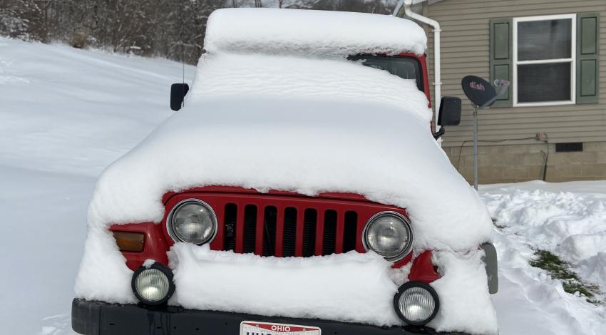 Front of red Jeep covered in snow