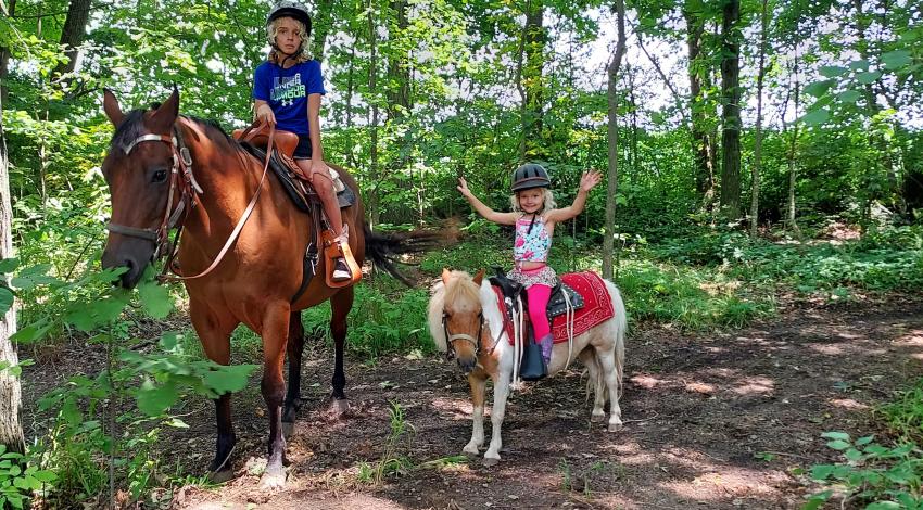 children on horseback on a wooded trail