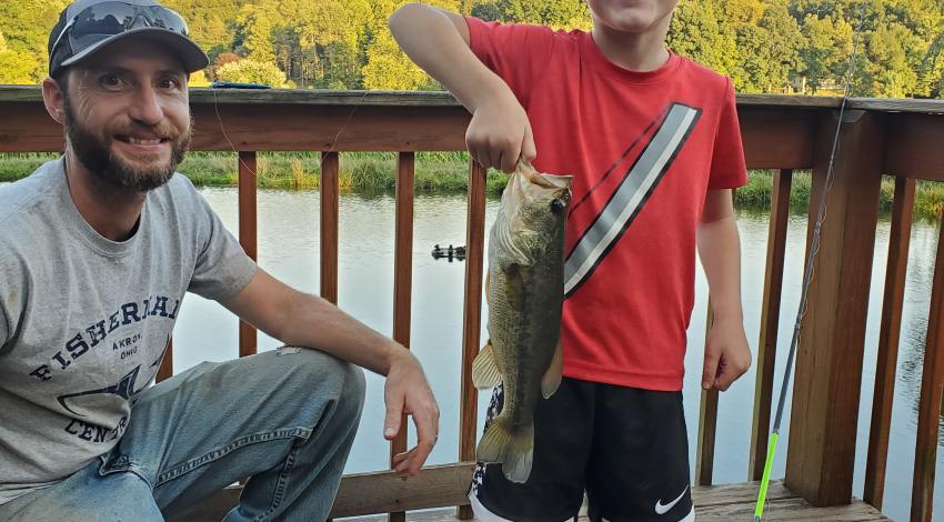 smiling boy with his dad holding a fish