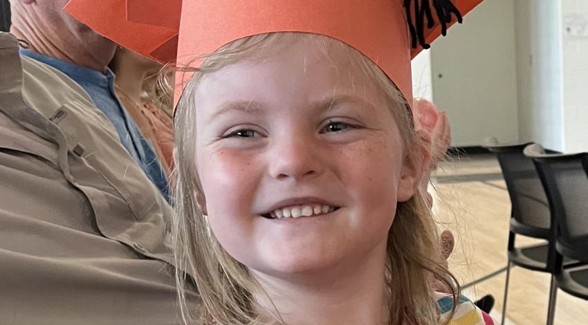little girl in orange graduation cap