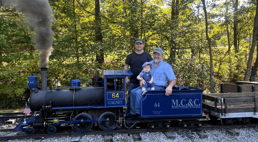 little boy with two men on miniature train