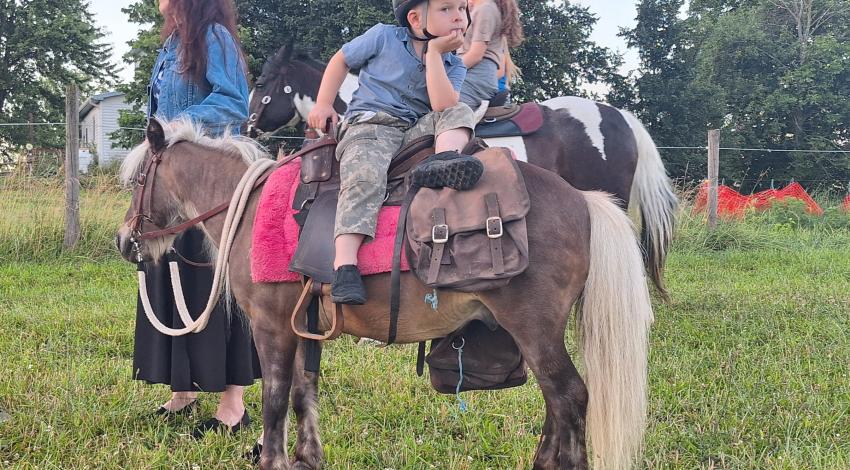 little boy sits backwards on pony