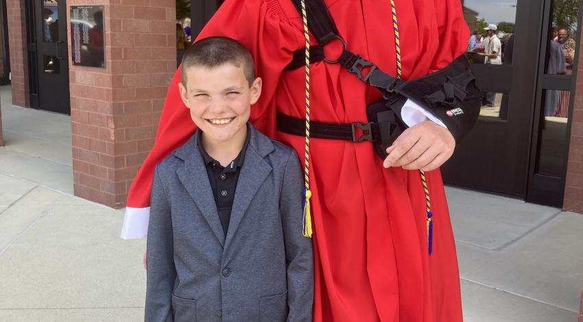 little boy with young man in red graduation gown